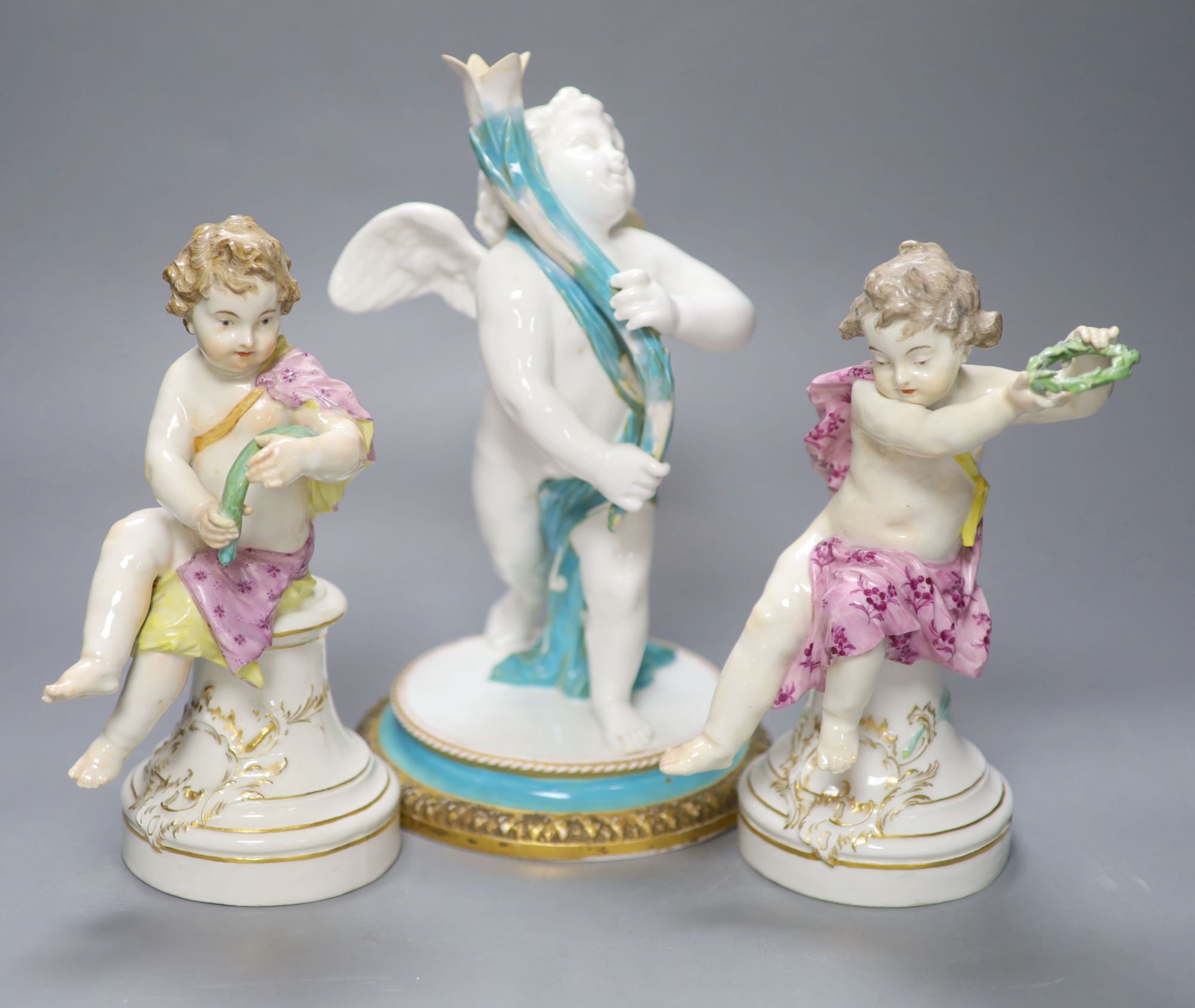 A pair of 19th century Berlin seated cherubs and a Continental porcelain figure of a cherub holding a cornucopia, tallest 27cm